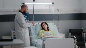 Asisstant with black skin arrange sick woman bed during sickness recovery / Photodune, Misc