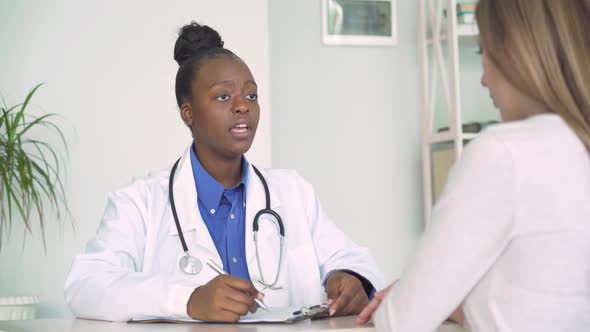 Professional African Doctor Consult Caucasian Woman Patient at Medical Visit