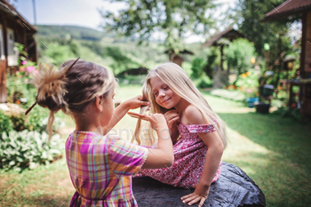 Girl brushing hair of her younger sister on the backyard of wooden house, healthy beauty / Photodune, Misc