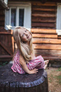 Blonde girl with long hair sitting on wood stub on backyard of old village house, healthy beauty / Photodune, Misc
