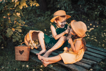 Children in overalls and straw hats eat pear while sitting on pallet / Photodune, Misc