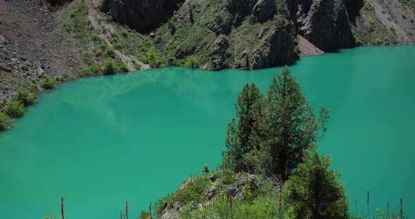Mountain Lake of green and blue color Urungach and pine trees. Located in Uzbekistan, Central Asia.
