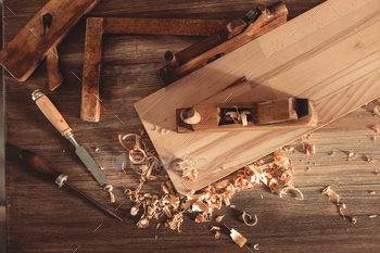 Plane jointer carpenter or joiner tool and wood shavings. Woodworking tools on wooden table / Photodune, Misc