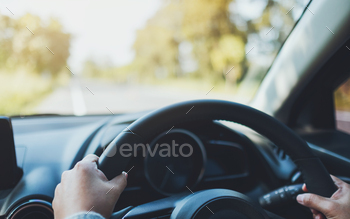 Closeup image of a woman holding steering wheel while driving a car on the road / Photodune, Misc