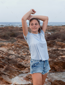 Teenage girl standing on cliff by the sea / Photodune, Misc