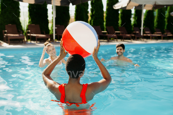 Smiling friends play with ball in the pool / Photodune, Misc