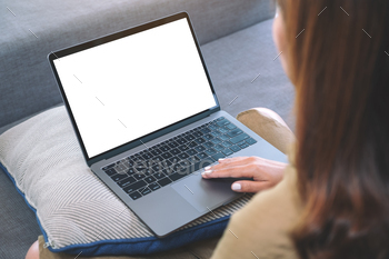 a woman using and touching on laptop touchpad with blank white screen while sitting in living room / Photodune, Misc