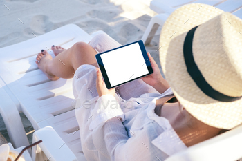 a woman holding a black tablet pc with blank desktop screen on the beach / Photodune, Misc