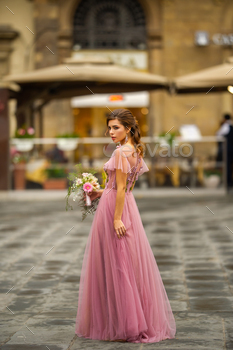 A bride in a pink dress with a bouquet stands in the center of the Old City of Florence in Italy / Photodune, Misc