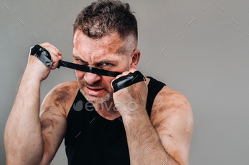on a gray background stands a battered man in a black T shirt looking like a fighter and preparing / Photodune, Misc