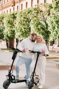 A couple in love in white clothes stands in the city on electric scooters with a drink in their / Photodune, Misc