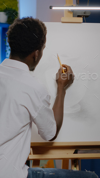 African american young adult using pencil on canvas drawing / Photodune, Misc