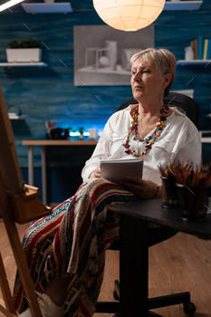 Old artist sitting in artwork studio with notebook / Photodune, Misc