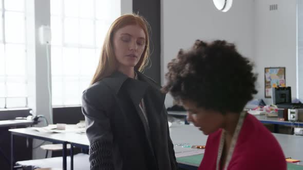 Mixed race woman dressing caucasian woman in fashion office