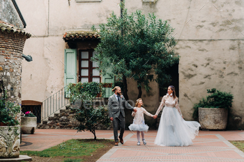 A happy young family walks through the old town of Sirmione in Italy.Stylish family in Italy on a / Photodune, Misc