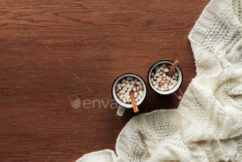 top view of mugs with delicious hot chocolate, marshmallows and cinnamon sticks on wooden background / Photodune, Misc