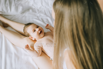 selective focus of happy mother playing with adorable baby boy in bed at home / Photodune, Misc