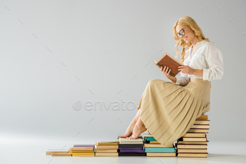 attractive smiling barefoot woman in glasses sitting on steps made of books / Photodune, Misc