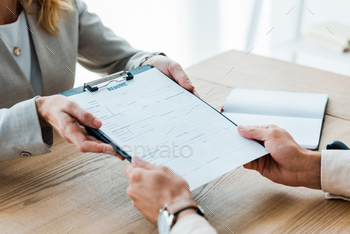 cropped view of recruiter giving clipboard with resume lettering to man / Photodune, Misc