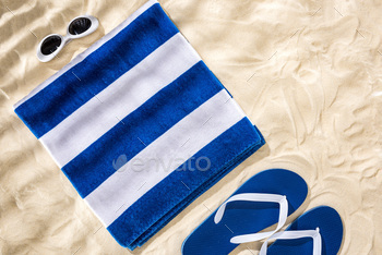 top view of white blue striped folded towel, retro sunglasses and flip flops on sand / Photodune, Misc