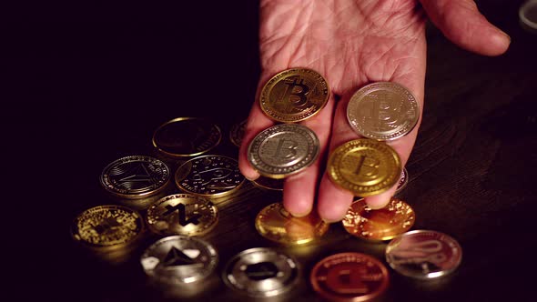 Man hand holding crypto coins and golden bitcoin on a table