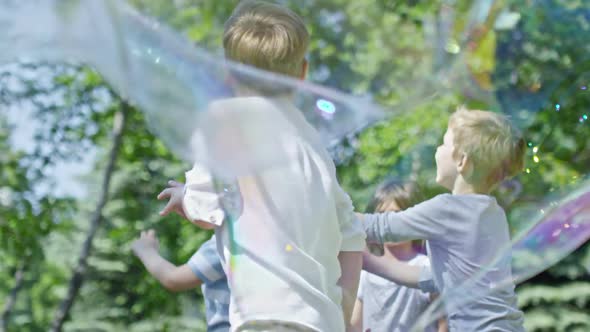 Kids Catching Bubbles in Park