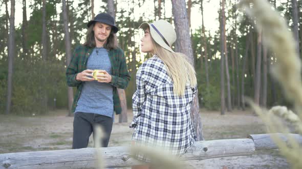 Back View of Young Caucasian Woman in Plaid Hipster Shirt and Hat Sitting in the Forest