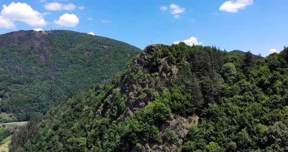 Cross At The Edge Of The Rocky Cliff And Lush Green Forest At Apuseni Mountains In Romania. aerial