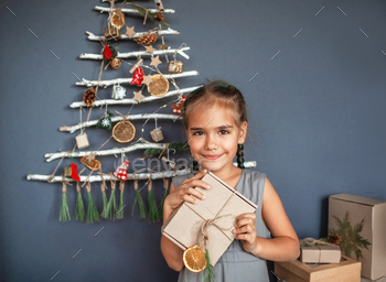 Girl near original Christmas tree made with branches, ecological toys, zero waste holidays / Photodune, Misc