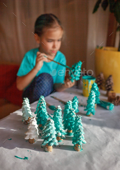 DIY craft gifts and Christmas decoration. Girl coloring cone as if it is pine tree, be green / Photodune, Misc