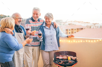 Happy senior friends having fun drinking red wine at barbecue dinner in terrace / Photodune, Misc