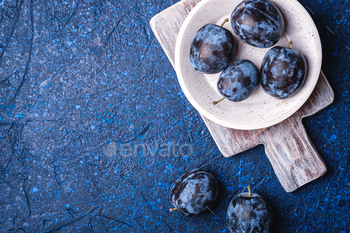 Fresh ripe plum fruits in white wooden bowl and old cutting board / Photodune, Misc