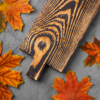 Handcrafted old wooden cutting board with autumn leaves on concrete background / Photodune, Misc