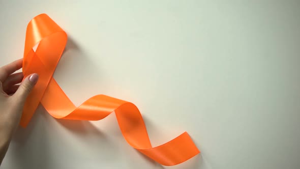 Female Placing Orange Ribbon on Table, Leukemia Awareness Campaign, Precaution