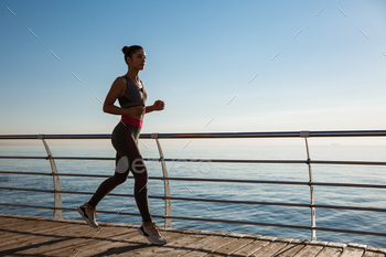 Side view of fitness woman running along seaside promenade, workout on fresh air near the sea / Photodune, Misc