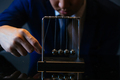 Cropped shot of businessman pulling ball of Newton cradle - PhotoDune Item for Sale