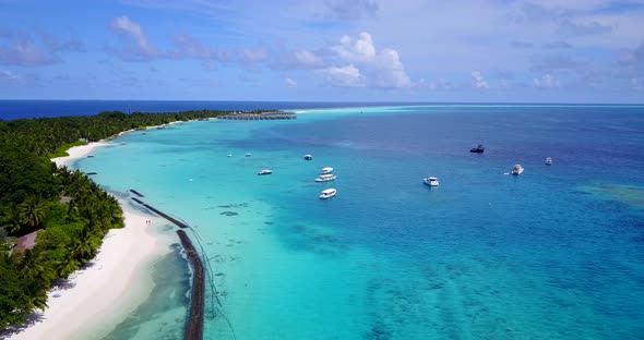 Wide angle drone travel shot of a sunshine white sandy paradise beach and aqua blue ocean background