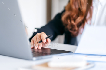 Businesswoman using and working on laptop computer and paperwork in office / Photodune, Misc