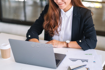 Closeup image of businesswoman using and typing on laptop while working in office / Photodune, Misc