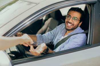 nd taking automatic car key from leasing or renting service person, seller. Smiling indian guy doing test-drive before buying new automobile