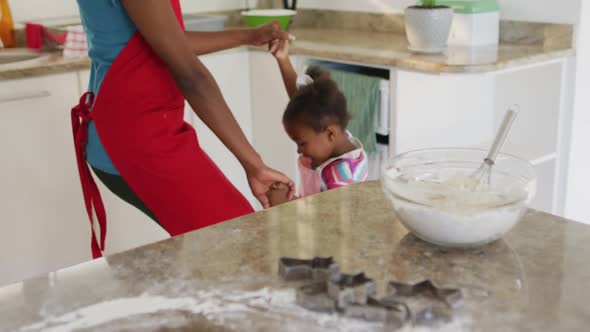 Happy african american mother and daughter dancing and having fun in kitchen