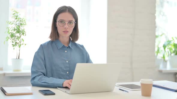 Young Woman Working on Laptop and Smiling at Camera