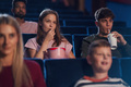 Front view of cheerful young couple with drink and popcorn in the cinema, watching film - PhotoDune Item for Sale