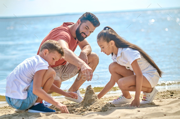 A dad with kids making sand castles / Photodune, Misc