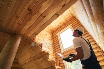 Male worker clicking on laptop while checking house walls / Photodune, Misc