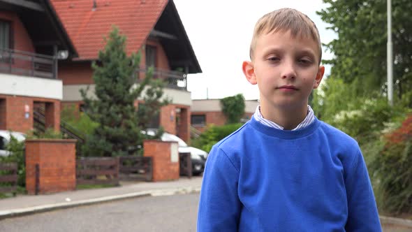 A Young Boy Looks Seriously at the Camera in a Suburban Street