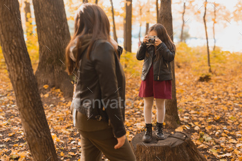Child taking picture her mother on retro camera in autumn park. Hobbies and leisure concept / Photodune, Misc