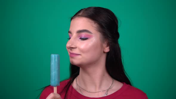 Beauty Brunette Woman Eating Ice Cream Enjoying Sweets on Blue Background