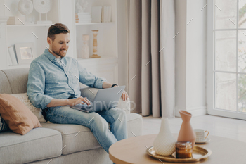 Young attractive smiling freelancer working on comfortable sofa at home / Photodune, Misc