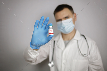 Doctor in medical mask and gloves holding ampoule and syringe with coronavirus vaccine, cold and flu / Photodune, Misc